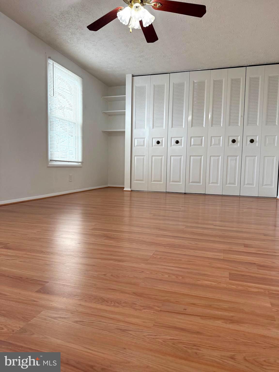 19445 Breezedale Lane Germantown, MD 20876 - Photo 10 of 16 an empty room with wooden floor chandelier fan and windows