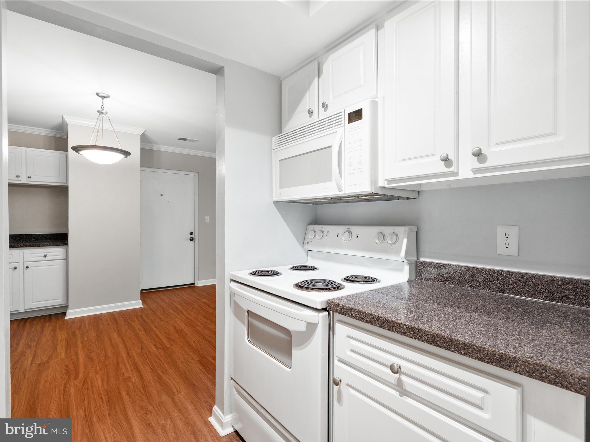 18334 Streamside Drive, Unit 101 Gaithersburg, MD 20879 - Photo 12 of 29 a kitchen with granite countertop a stove and a white countertops with wooden floor