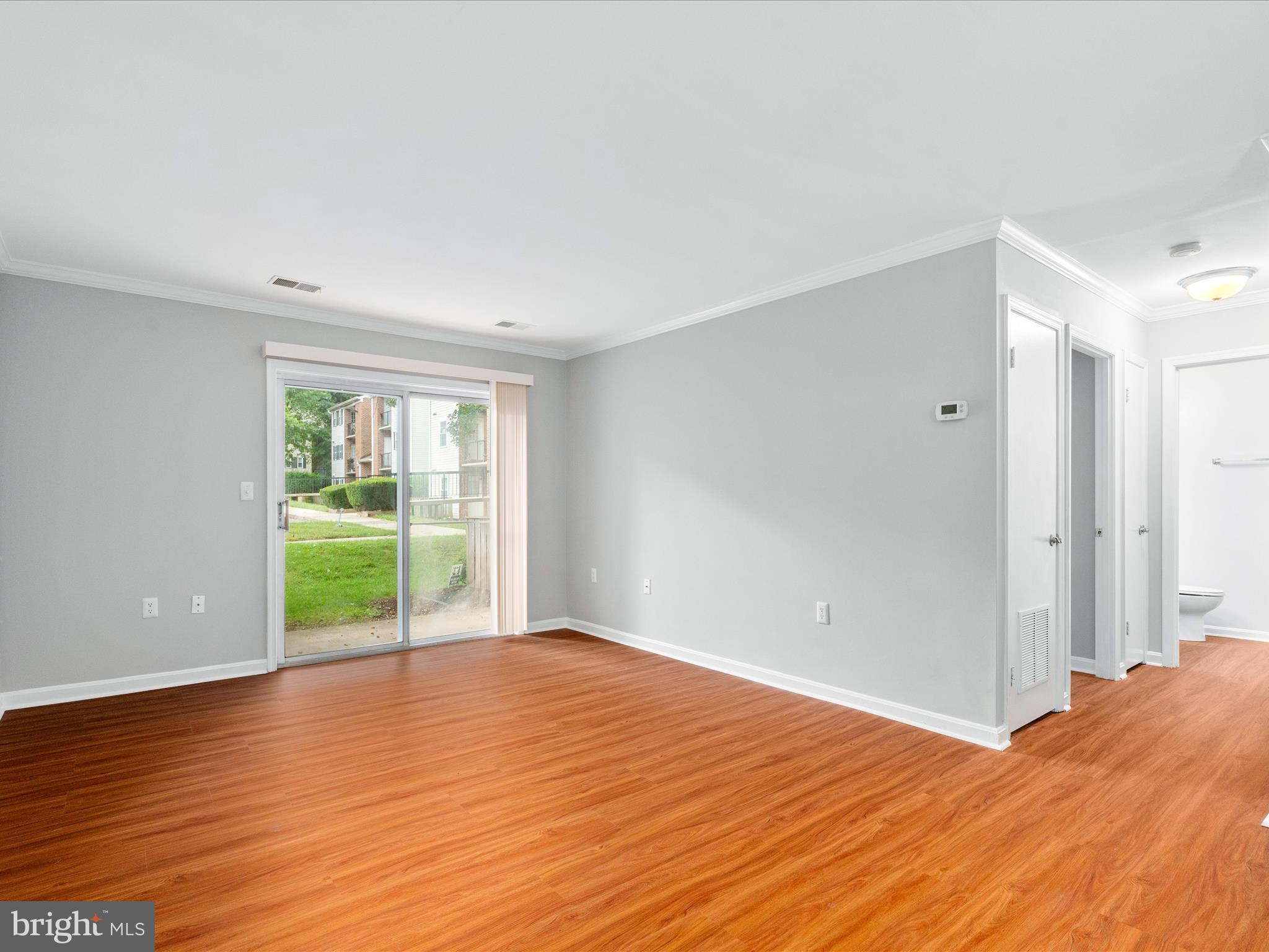 18334 Streamside Drive, Unit 101 Gaithersburg, MD 20879 - Photo 3 of 29 a view of an empty room with wooden floor and a window