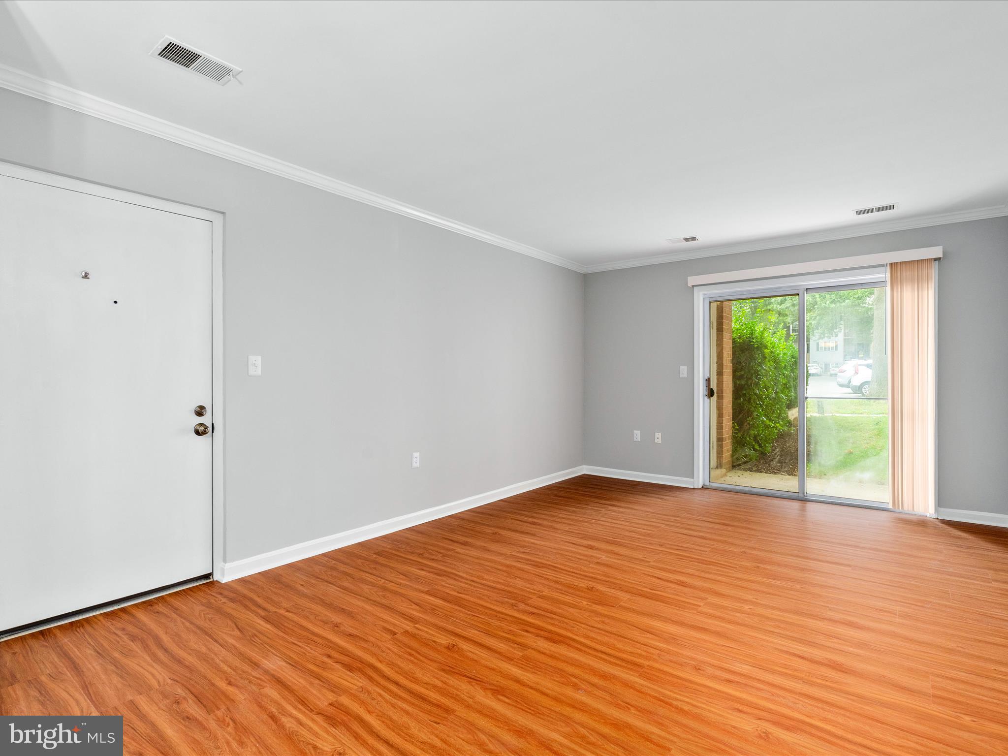 18334 Streamside Drive, Unit 101 Gaithersburg, MD 20879 - Photo 4 of 29 a view of an empty room with wooden floor and a window