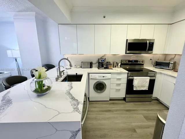 a kitchen with a stove a sink and white cabinets