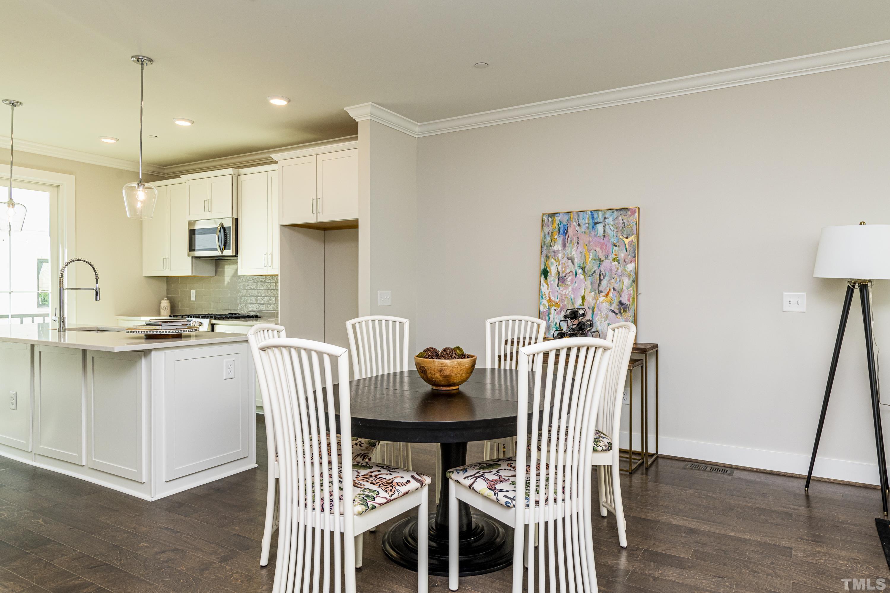 401 Bryan Pointe Drive, Unit 102 Raleigh, NC 27608 - Photo 11 of 30 a kitchen with a dining table chairs and white cabinets
