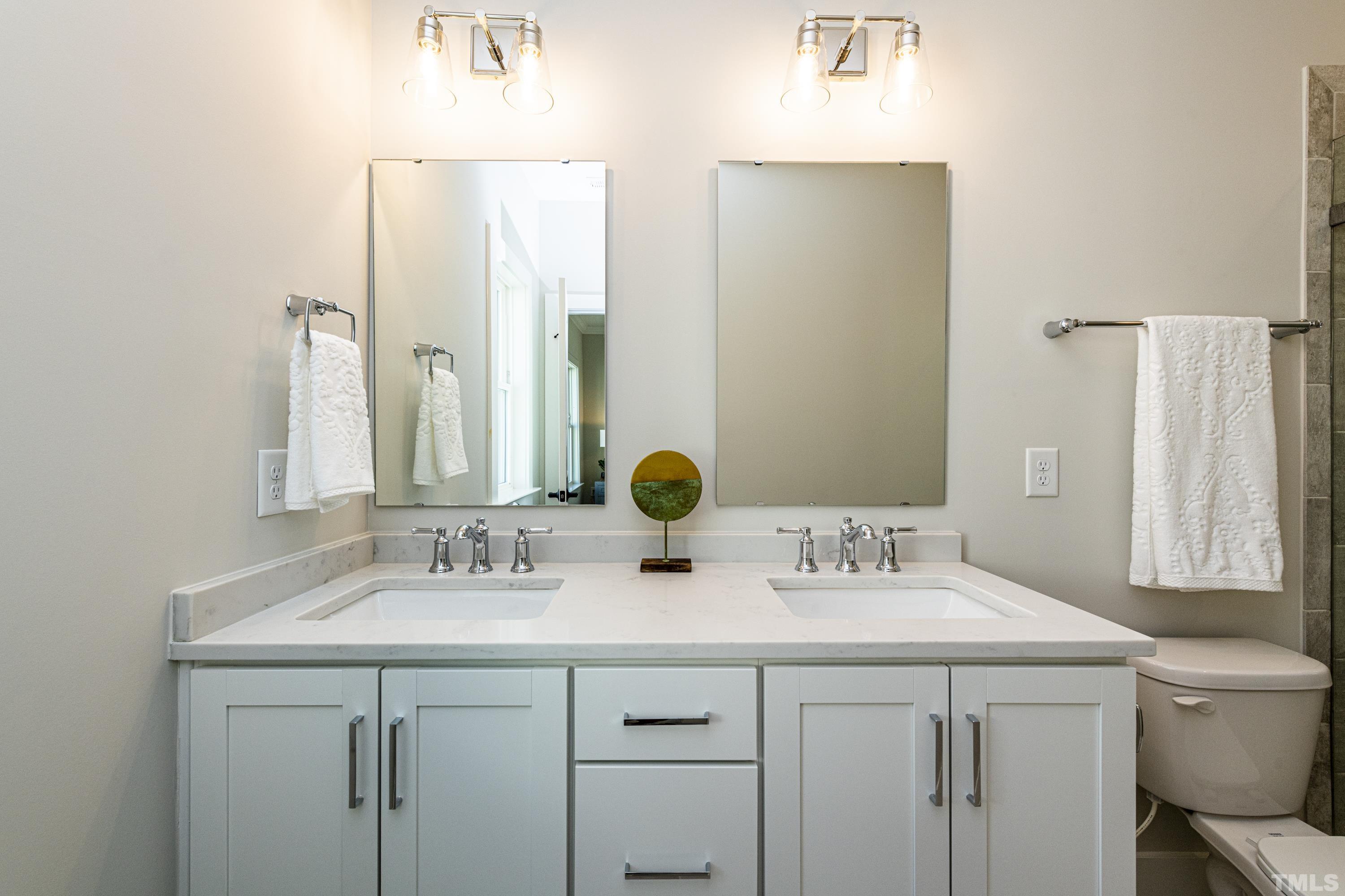 401 Bryan Pointe Drive, Unit 102 Raleigh, NC 27608 - Photo 23 of 30 a bathroom with a double vanity sink and a mirror