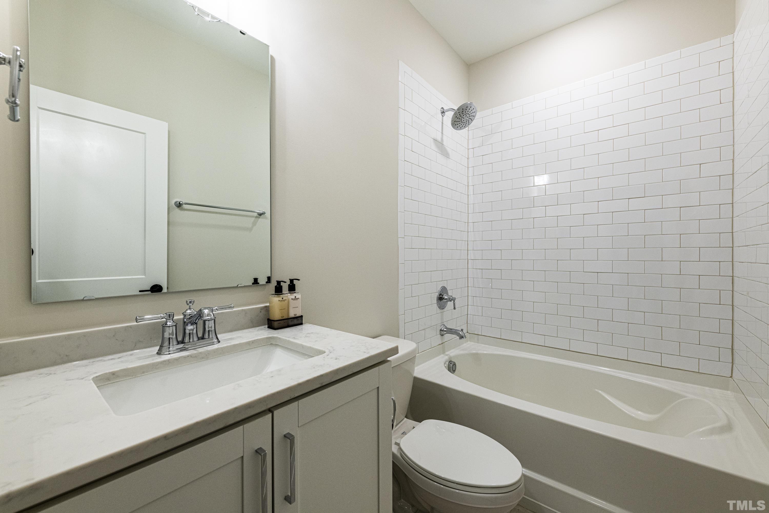 401 Bryan Pointe Drive, Unit 102 Raleigh, NC 27608 - Photo 6 of 30 a bathroom with a granite countertop bathtub shower sink vanity mirror and toilet