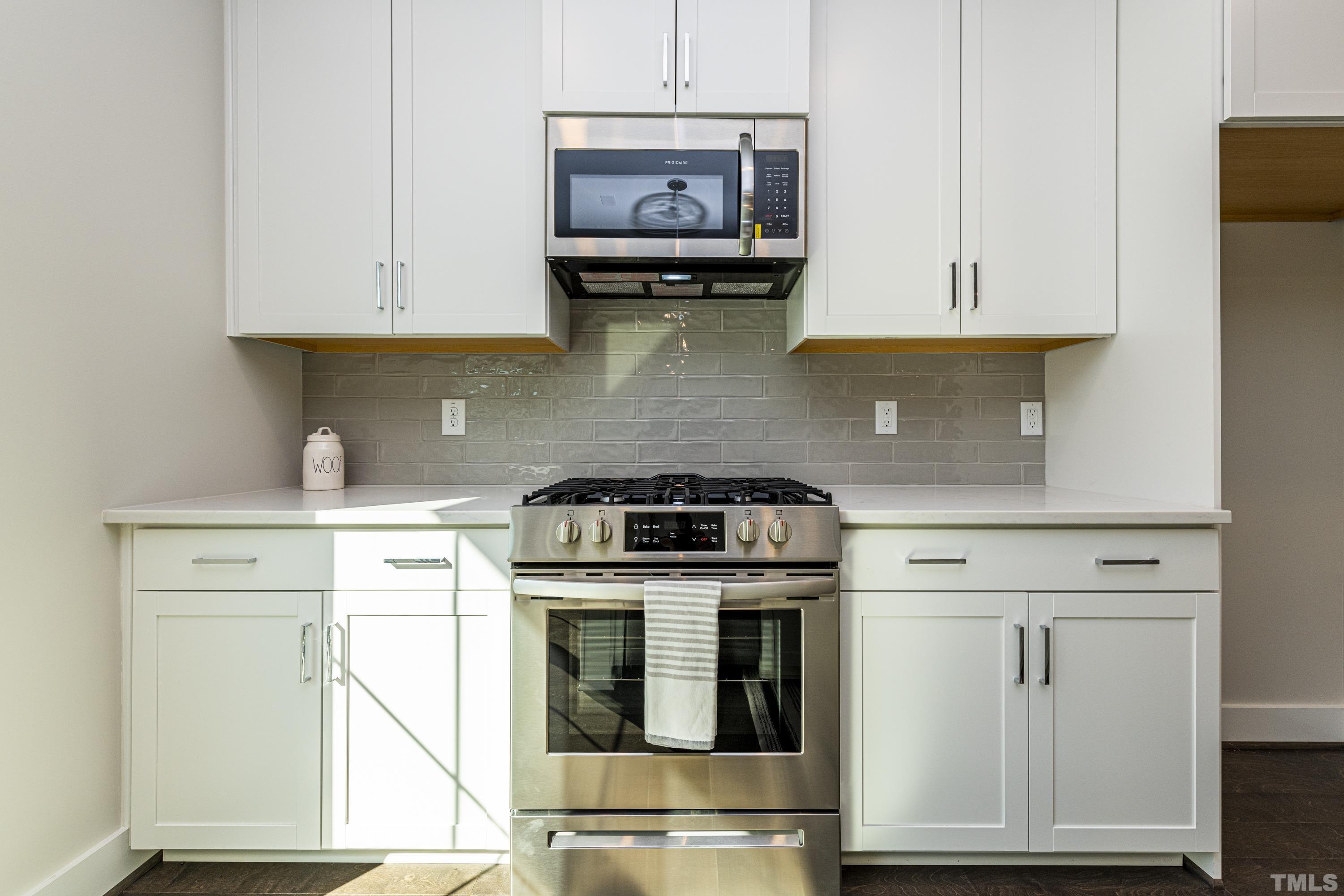 401 Bryan Pointe Drive, Unit 102 Raleigh, NC 27608 - Photo 8 of 30 a kitchen with stainless steel appliances granite countertop a stove a sink and a microwave