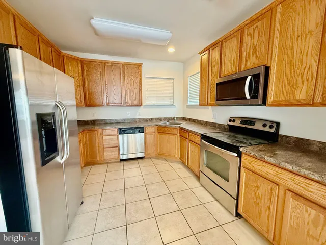 a kitchen with stainless steel appliances granite countertop a refrigerator a stove top oven and sink