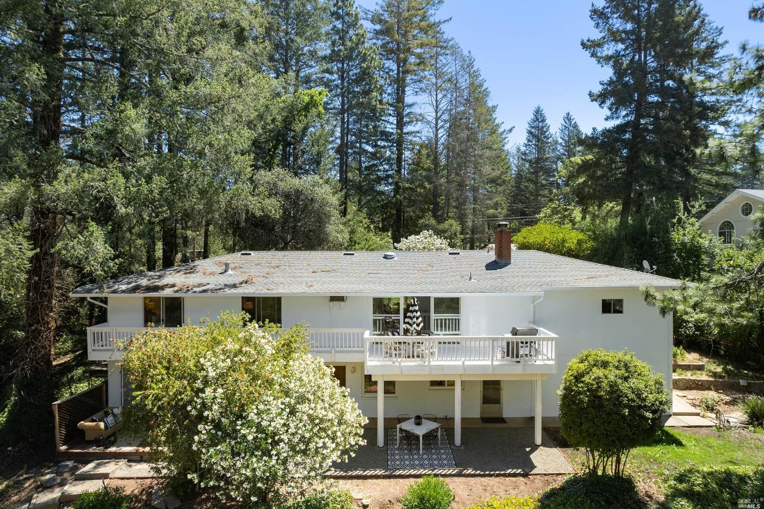 a view of a white house next to a yard with a table and chairs