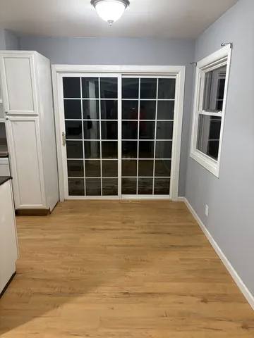 a view of an empty room with wooden floor and a window