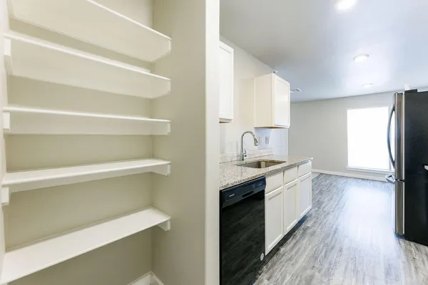 a view of a kitchen with stainless steel appliances wooden floor and chair