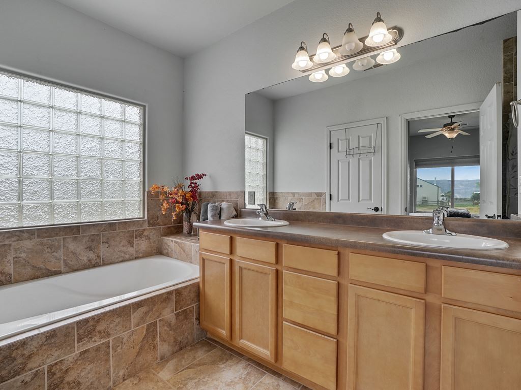 1853 Golden Ranch Road Fruita, CO 81521 - Photo 14 of 30 a bathroom with a tub a double vanity sink a window and a mirror