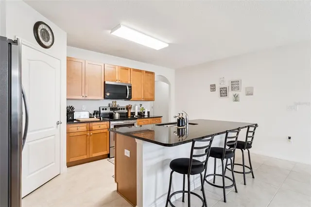 a kitchen with stainless steel appliances granite countertop a dining table chairs refrigerator and microwave