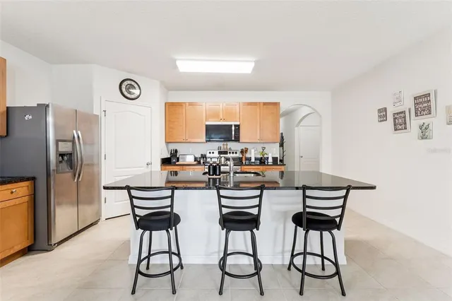 a kitchen with stainless steel appliances a dining table chairs refrigerator and sink
