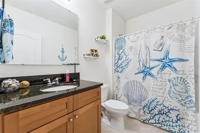 a bathroom with a granite countertop sink and a toilet
