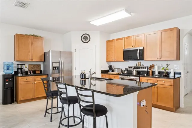 a kitchen with stainless steel appliances granite countertop a sink a stove a refrigerator cabinets and a dining table with wooden floor