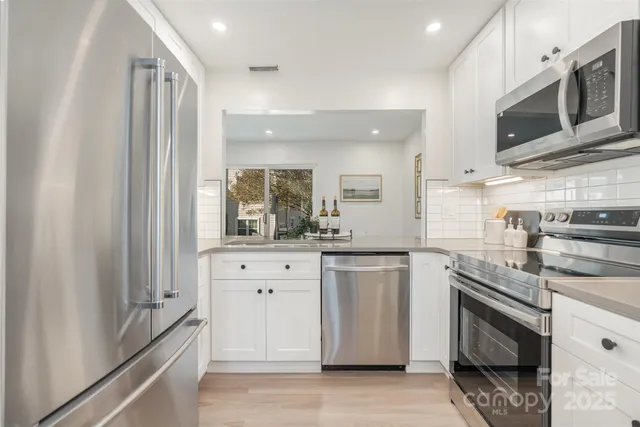 a kitchen with stainless steel appliances white cabinets and a refrigerator