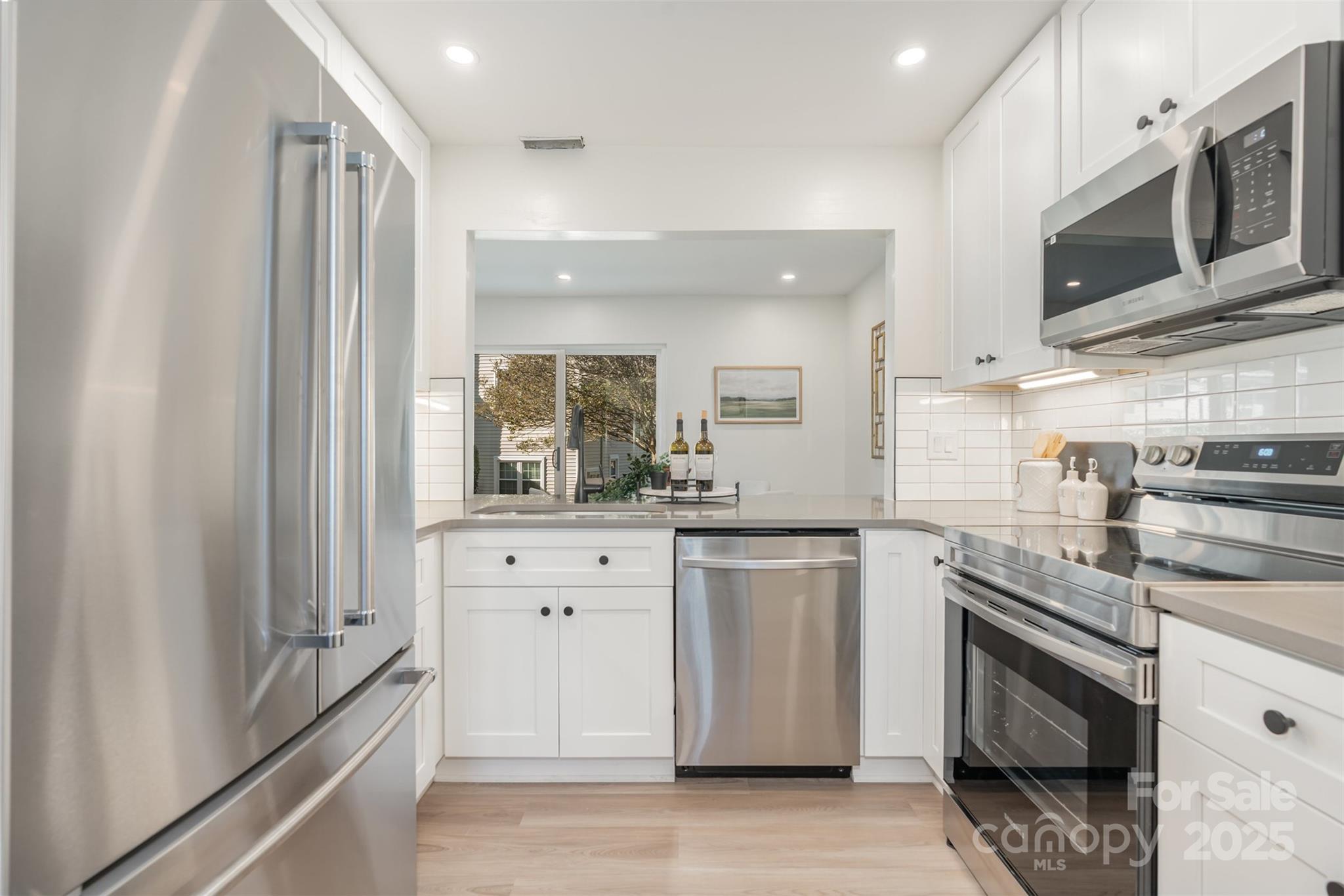7802 Renaissance Court, Unit B Charlotte, NC 28226 - Photo 10 of 22 a kitchen with stainless steel appliances granite countertop a refrigerator and a stove top oven