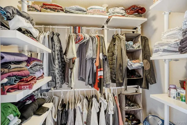 a view of walk in closet with clothes and shoes