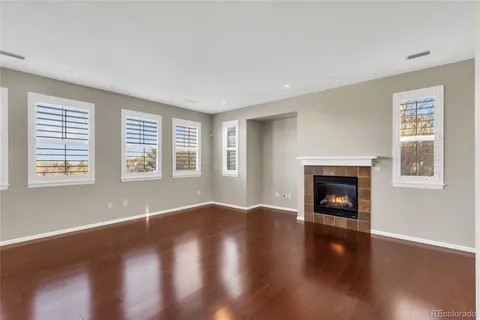 an empty room with wooden floor fireplace and windows