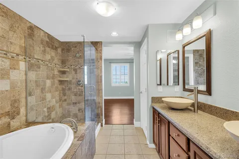 a bathroom with a granite countertop double vanity sink a mirror and a bathtub