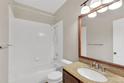 a bathroom with a granite countertop sink toilet and shower