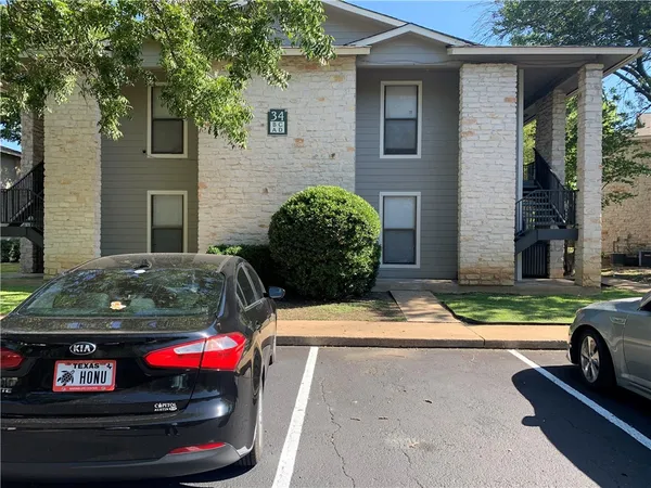 a view of a brick house with a cars park side of a road