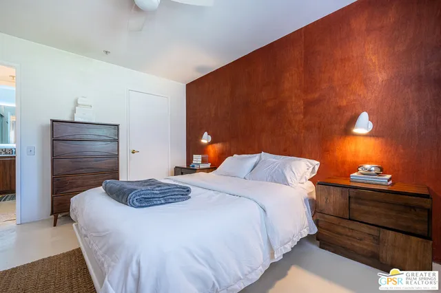 a bedroom with a bed and a lamp with the dresser