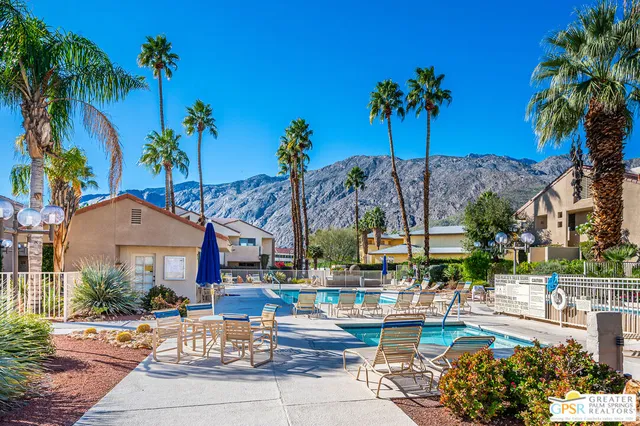 a view of a swimming pool with a table and chairs under palm trees