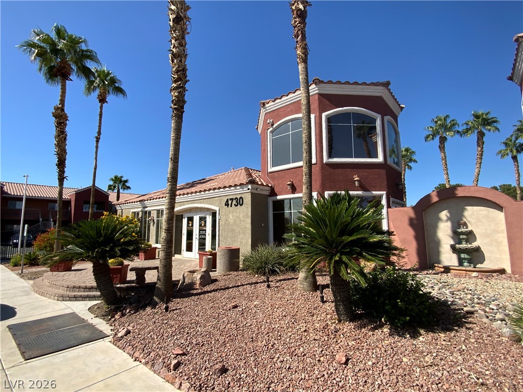 4730 East Craig Road, Unit 2029 Las Vegas, NV 89115 - Photo 4 of 4 A terracotta-colored structure, adorned with palm trees and a tiled roof, creates an inviting desert aesthetic.