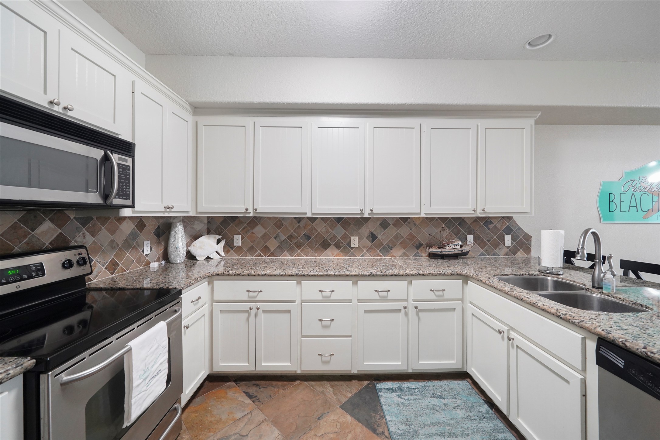 143 Boat Slip Road Matagorda, TX 77457 - Photo 12 of 31 a kitchen with granite countertop white cabinets and stainless steel appliances