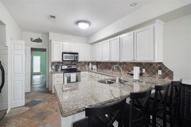 a kitchen with granite countertop a table chairs microwave and refrigerator