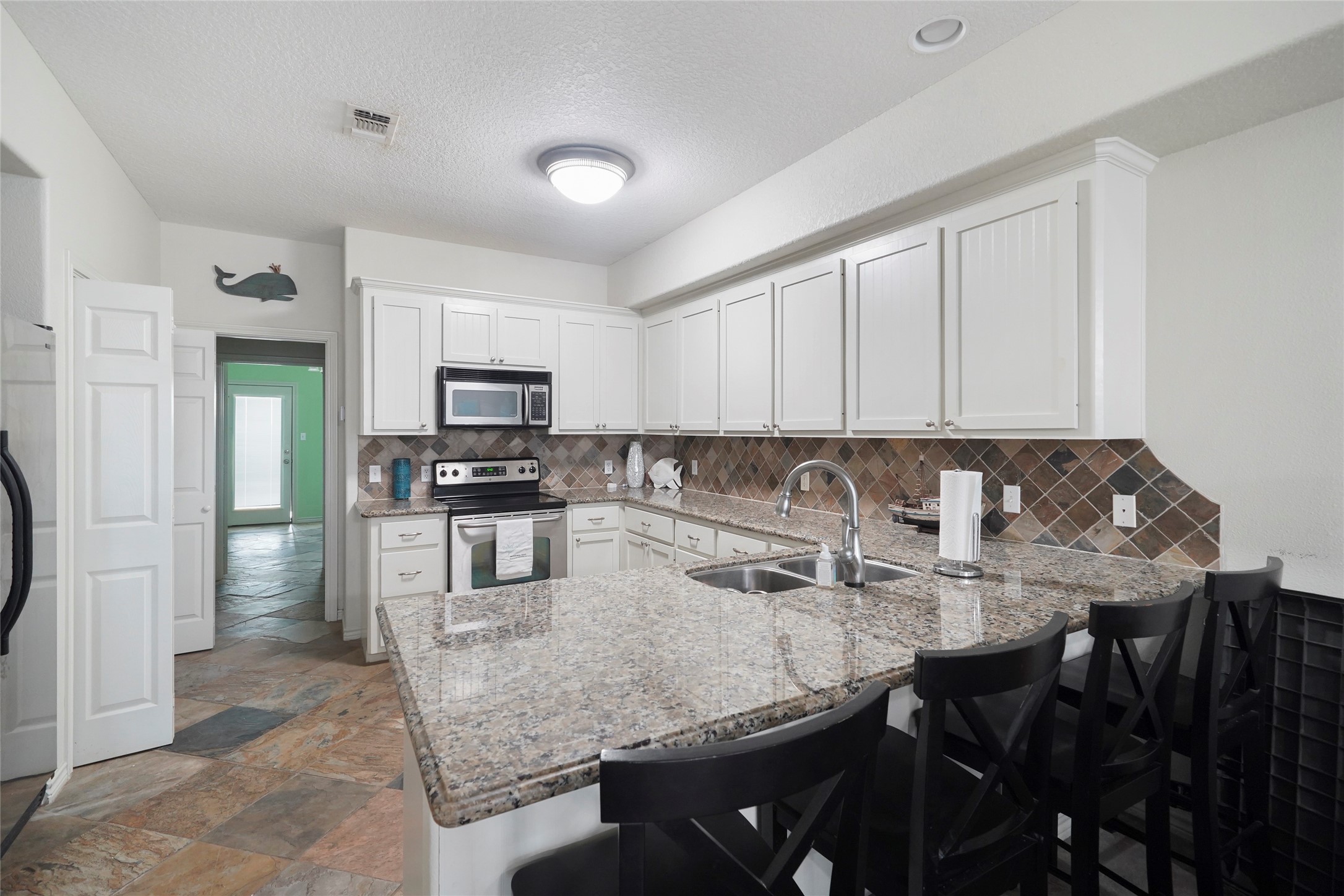 143 Boat Slip Road Matagorda, TX 77457 - Photo 9 of 31 a kitchen with granite countertop a table chairs microwave and refrigerator