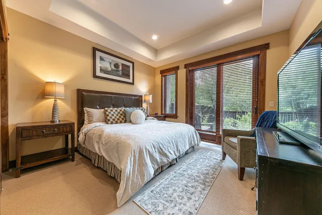 a bedroom with a balcony a bed and a large window