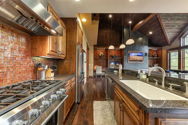 a kitchen with stainless steel appliances granite countertop a sink a stove and a wooden cabinets