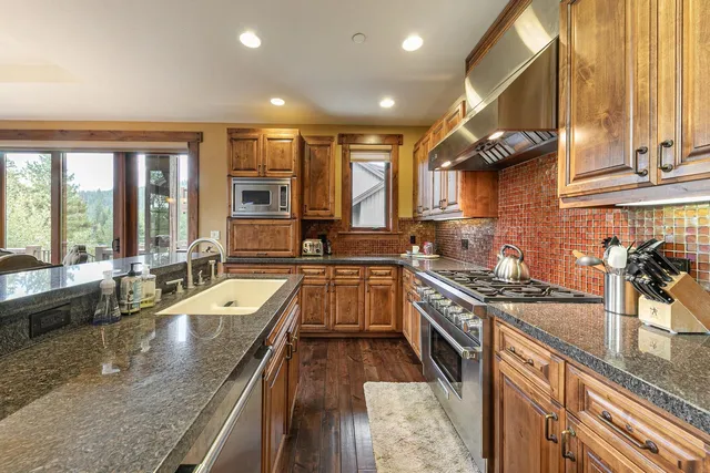 a kitchen with stainless steel appliances granite countertop sink stove top oven and cabinets