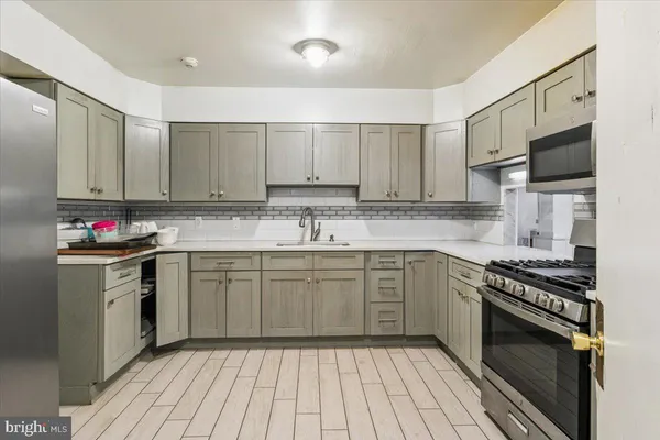 a kitchen with stainless steel appliances granite countertop a stove top oven a sink dishwasher and a refrigerator with wooden cabinets
