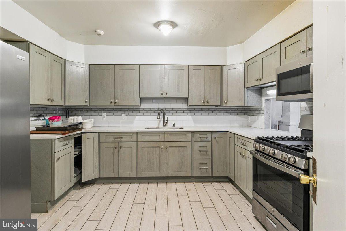 5205-07 Webster Street Philadelphia, PA 19143 - Photo 7 of 37 a kitchen with stainless steel appliances granite countertop a stove top oven a sink dishwasher and a refrigerator with wooden cabinets