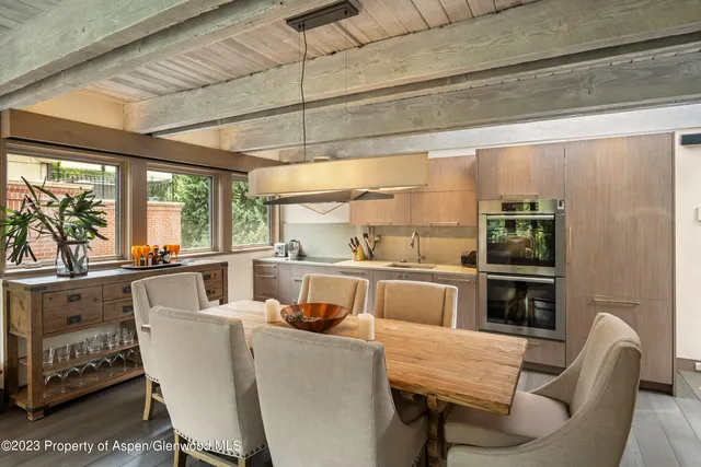 a dining room with stainless steel appliances furniture large window and wooden floor