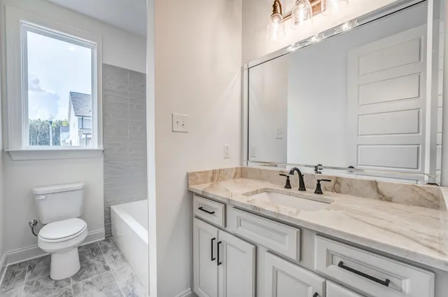 a bathroom with a granite countertop toilet a sink and a mirror