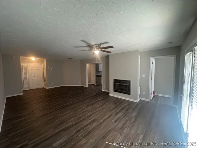 an empty room with wooden floor fireplace and windows
