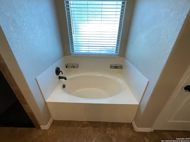 a view of an empty room with a ceiling fan and window