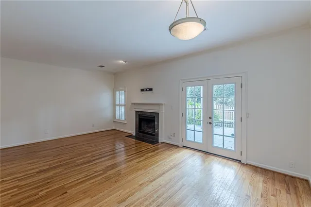 an empty room with wooden floor fireplace and window