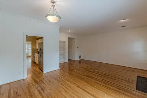 a view of empty room with wooden floor and fan
