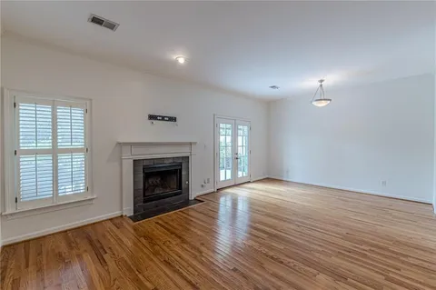 an empty room with wooden floor fireplace and windows