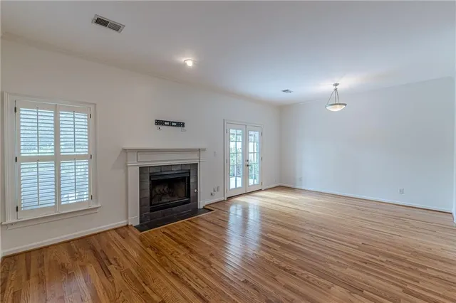 an empty room with wooden floor fireplace and windows