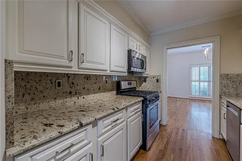 a kitchen with granite countertop a sink a stove and cabinets