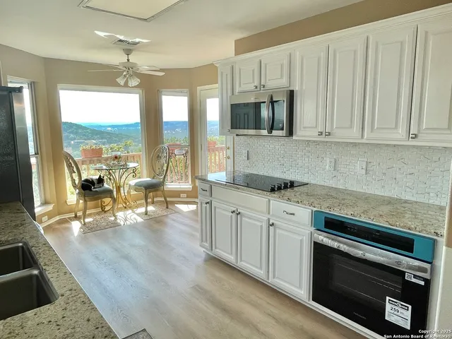 a kitchen with stainless steel appliances granite countertop a stove a sink dishwasher and a microwave oven with white cabinets