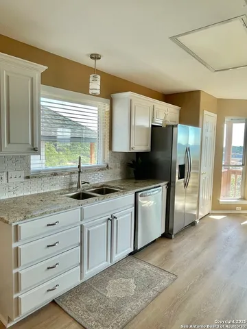 a kitchen with granite countertop a stove a sink and a refrigerator