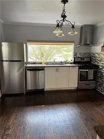 a view of a kitchen with wooden floor and stainless steel appliances