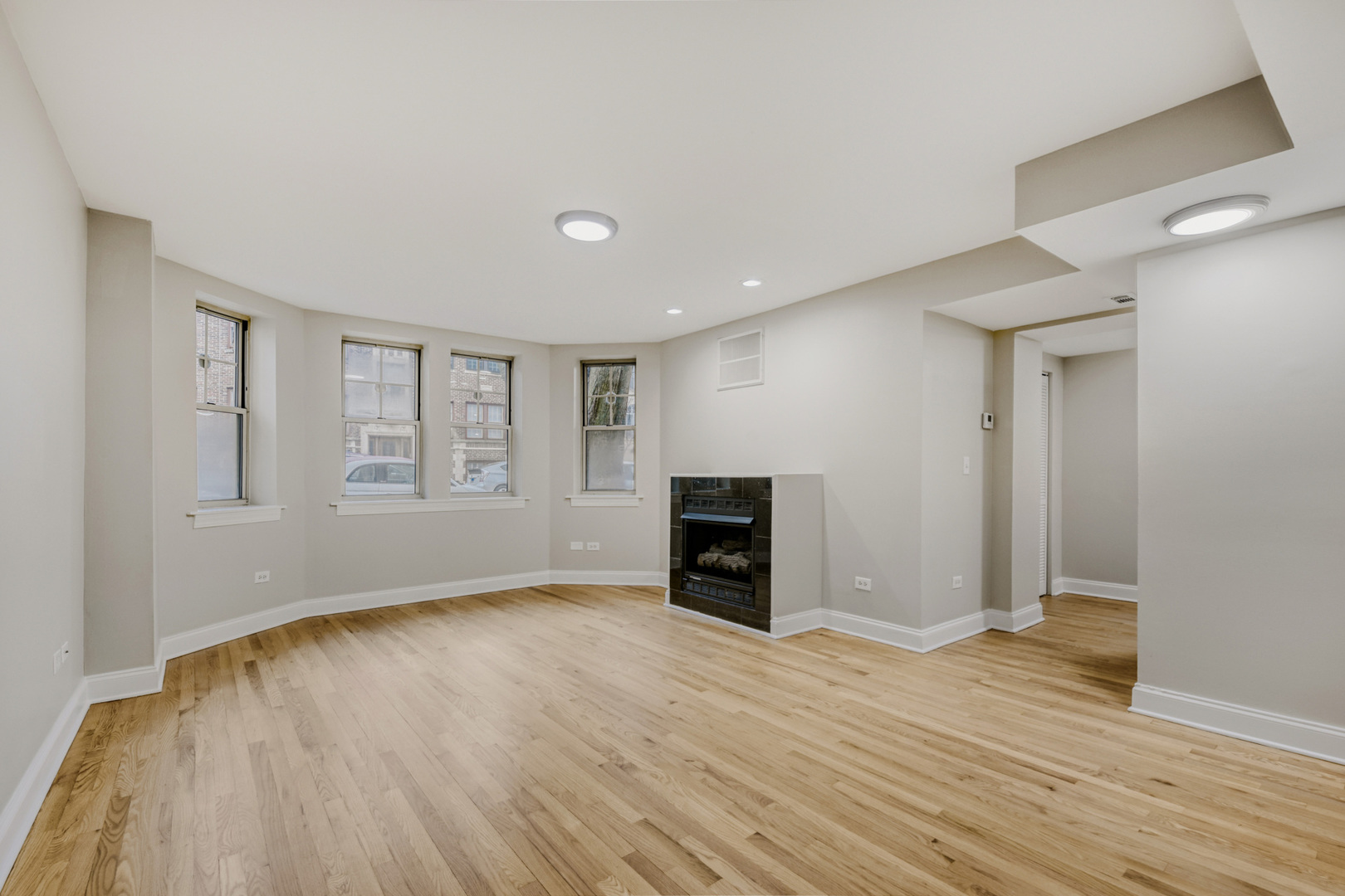 6450 North Bell Avenue, Unit G Chicago, IL 60645 - Photo 3 of 18 a view of an empty room with wooden floor fireplace and a window