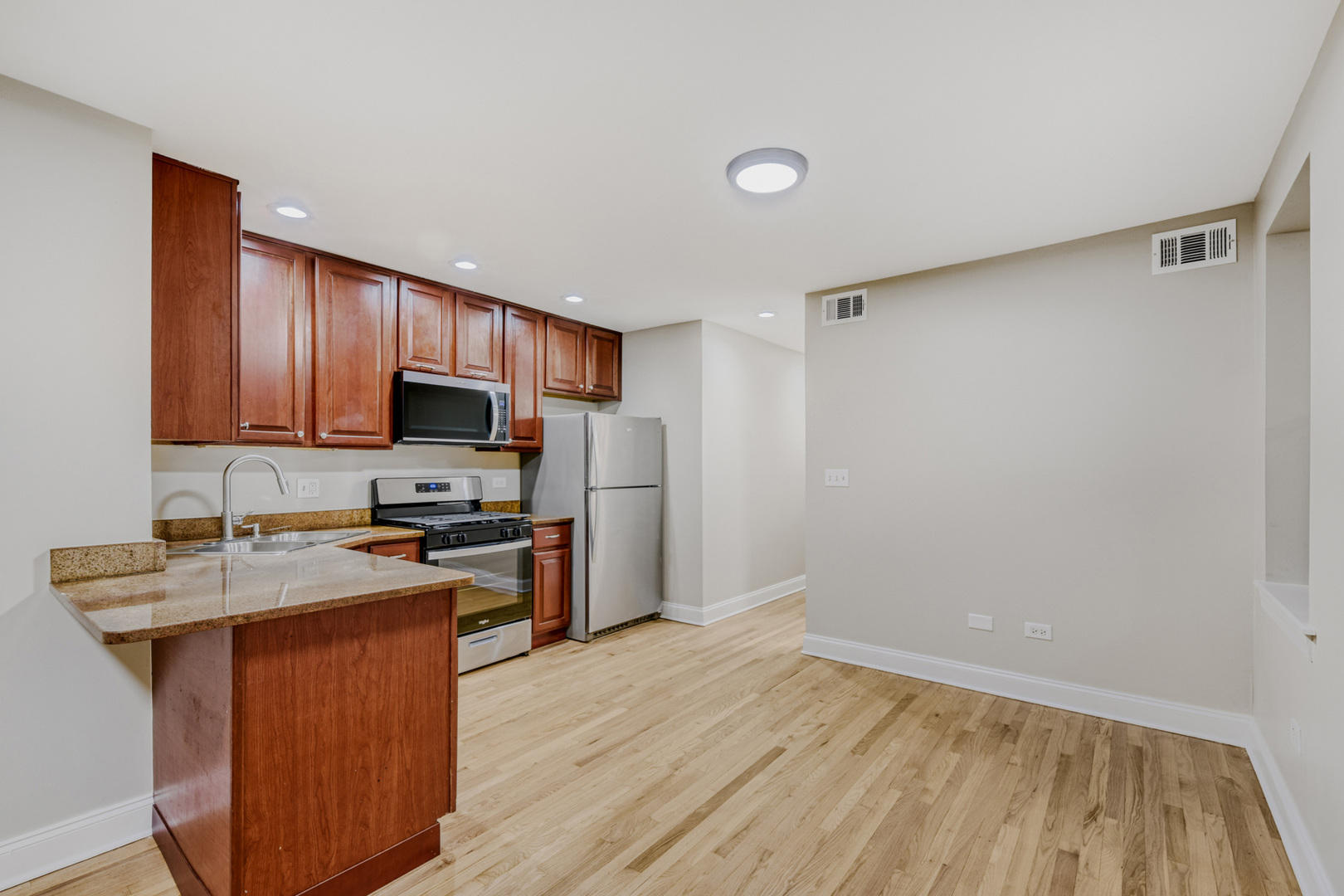 6450 North Bell Avenue, Unit G Chicago, IL 60645 - Photo 8 of 18 a kitchen with a sink a stove a refrigerator cabinets and wooden floor